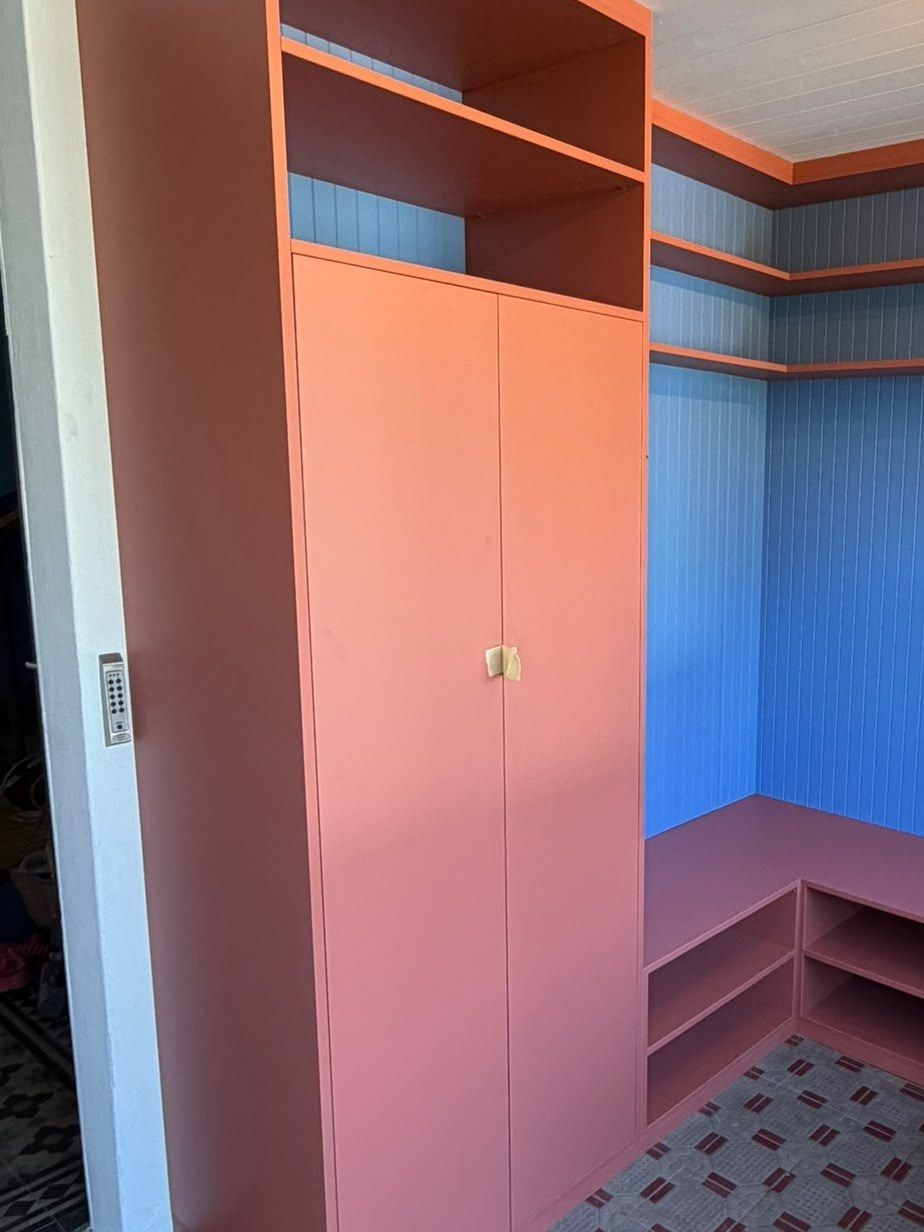 Le même angle équipé d’un aménagement sur mesure : armoire corail, étagères et banc à casiers sur fond bleu