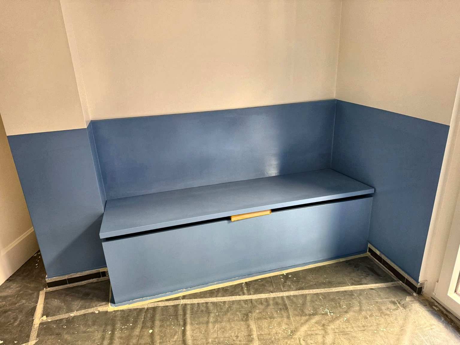 Banquette coffre sur mesure à finition bleue, assortie au soubassement du mur, réalisée à Genève