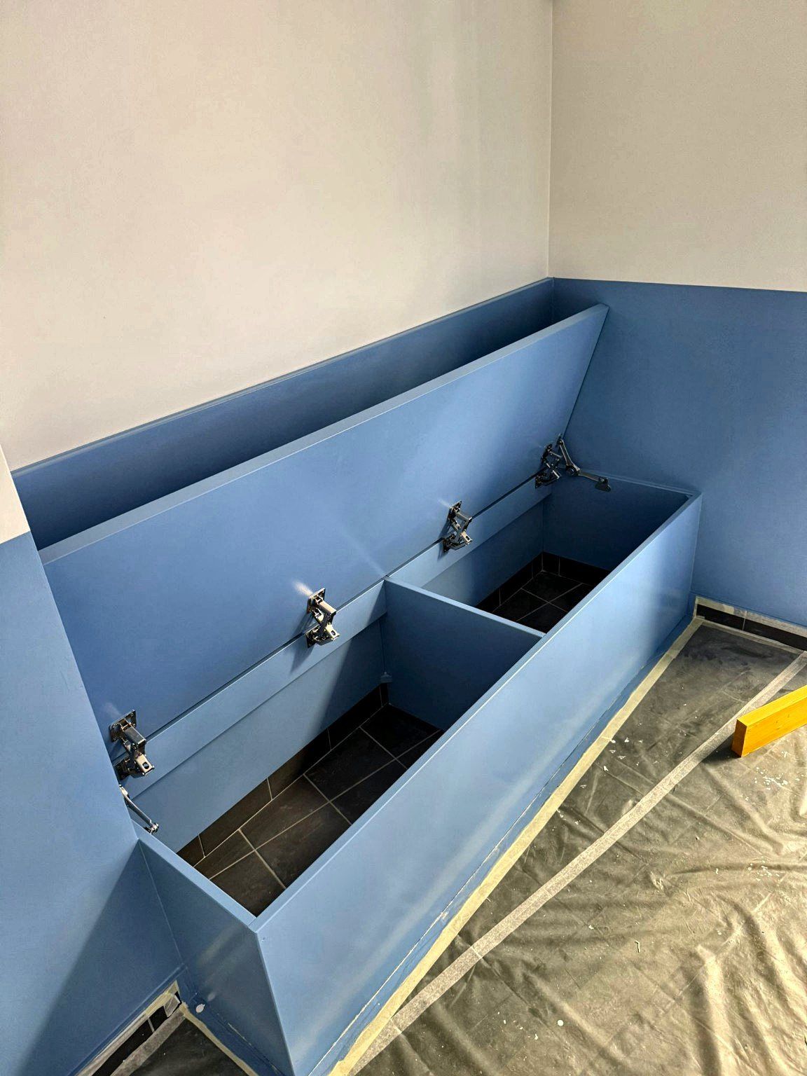 Coffres de rangement à abattants ouverts sous l’assise de la banquette