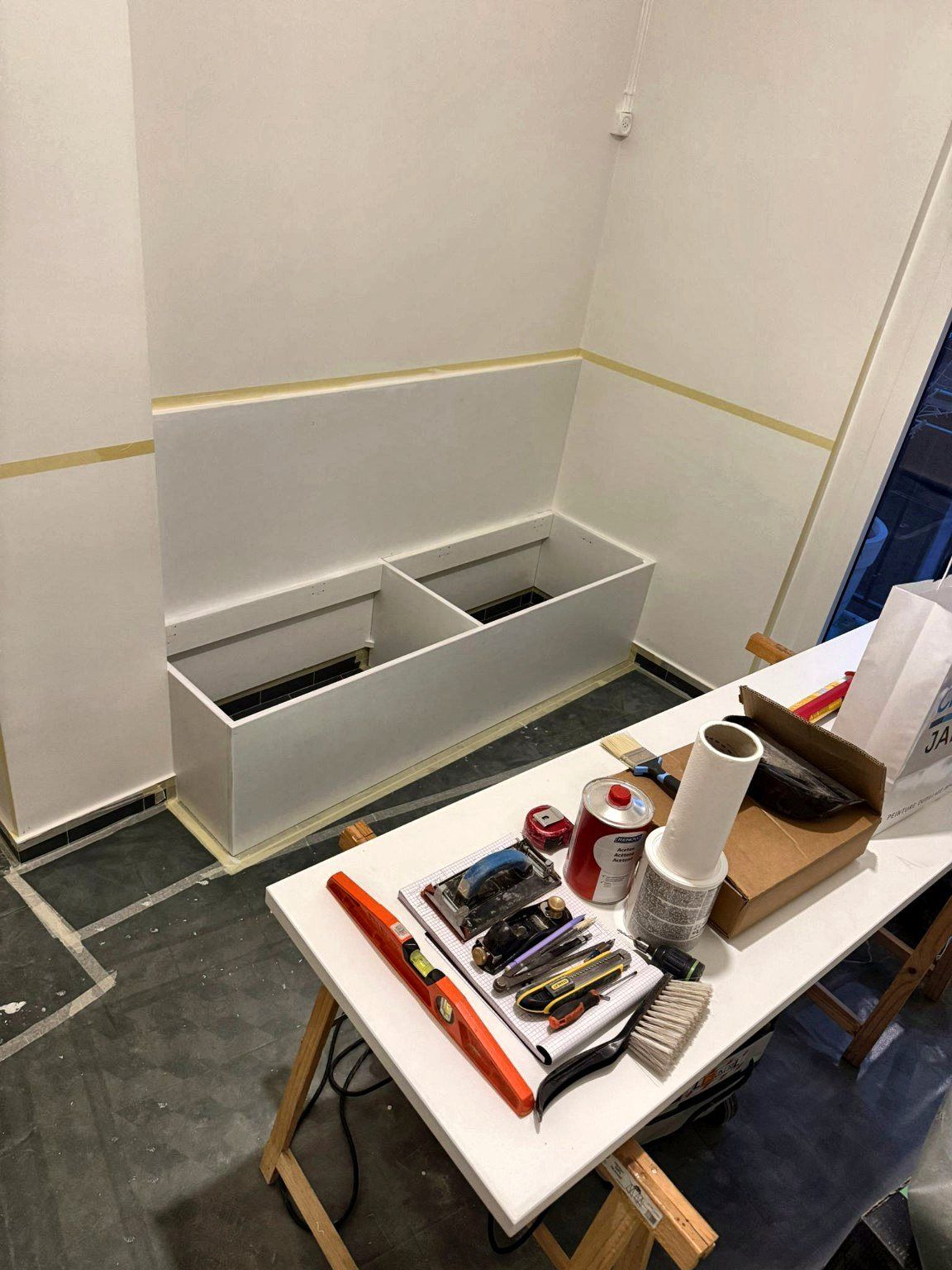Établi de chantier installé dans la pièce, pendant la fabrication sur place d’une banquette coffre à Genève