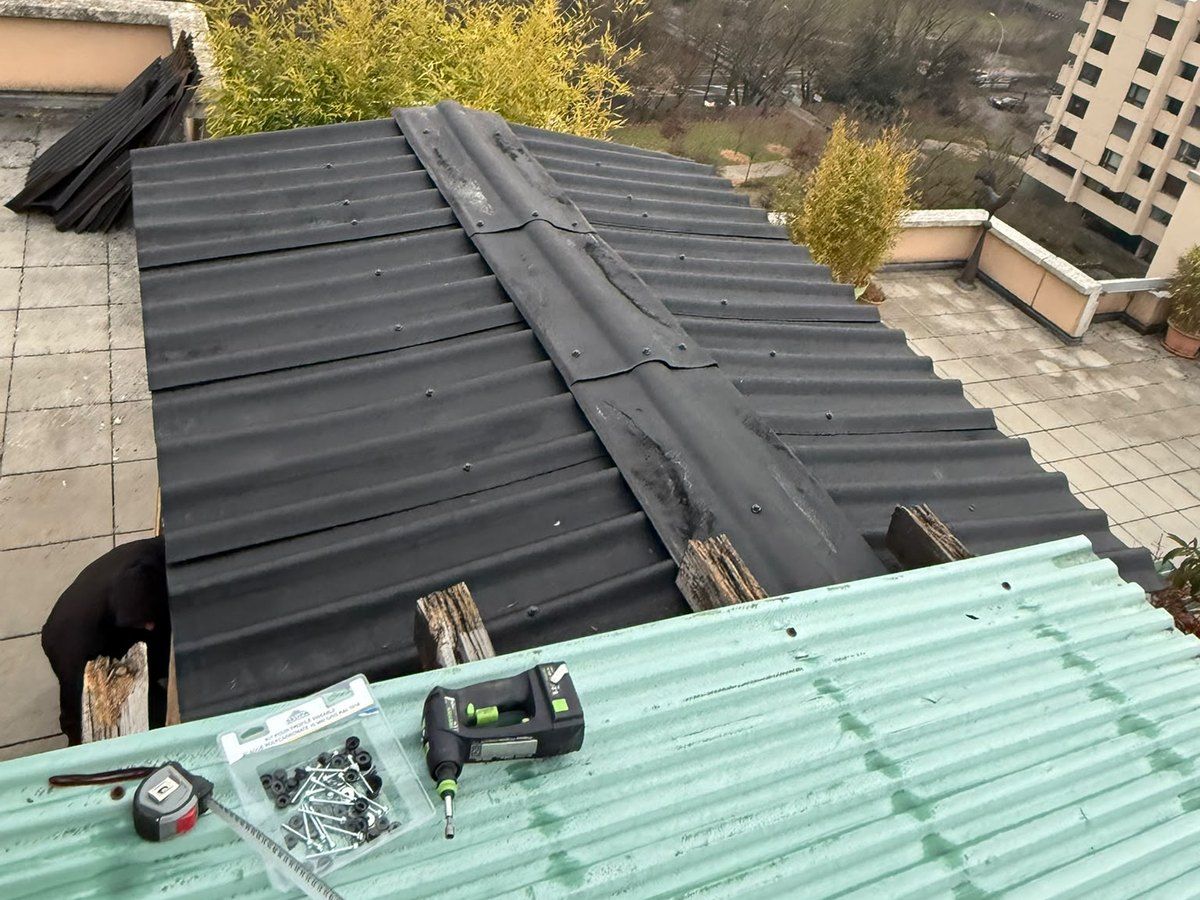 Toiture refaite en plaques ondulées noires sur un abri de terrasse, vue de dessus, avec les outils de pose au premier plan