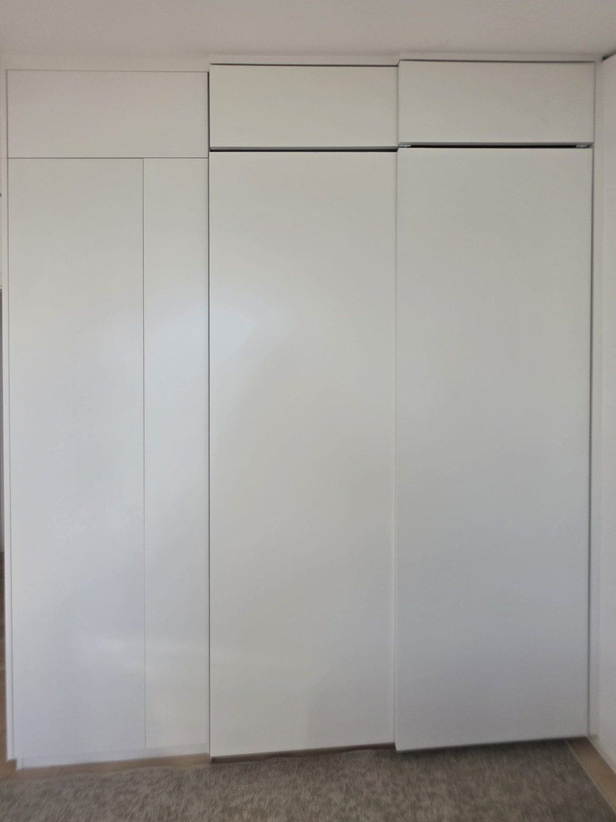 Armoire sur mesure fermée, façades blanches toute hauteur et caissons hauts