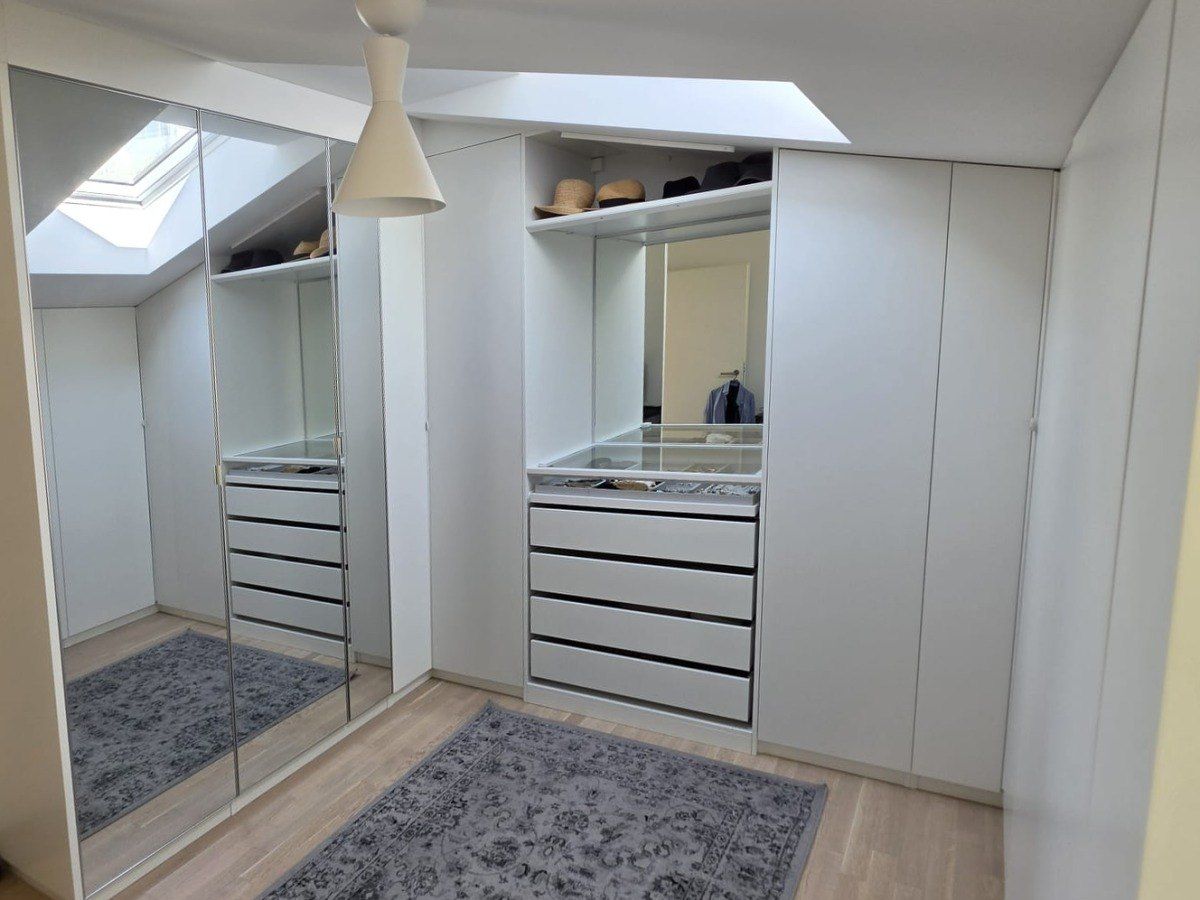 Dressing sur mesure blanc sous la pente du toit, avec miroir, tiroirs et puits de lumière