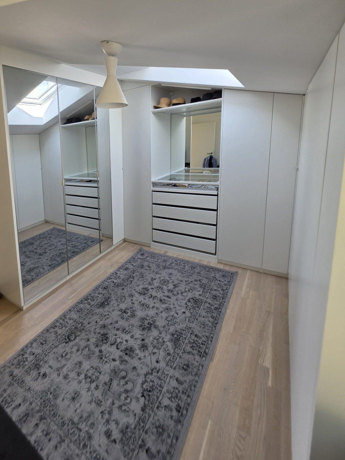 Dressing sur mesure blanc sous la pente du toit, avec miroir toute hauteur, tiroirs et puits de lumière