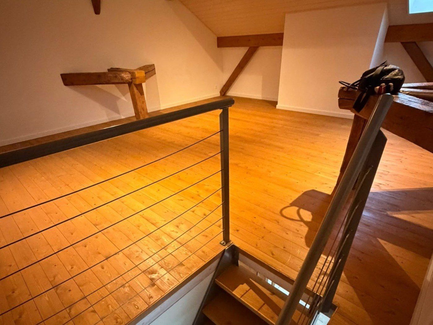 Le plancher sous combles avant travaux, à la teinte foncée et à la finition usée