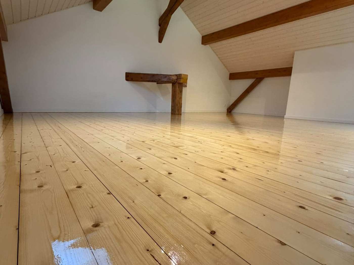 Plancher en bois sous combles, poncé et vitrifié, sous une charpente apparente