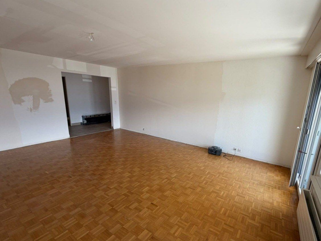 Séjour de l’appartement de Vevey avant travaux : parquet mosaïque d’origine et murs à reprendre