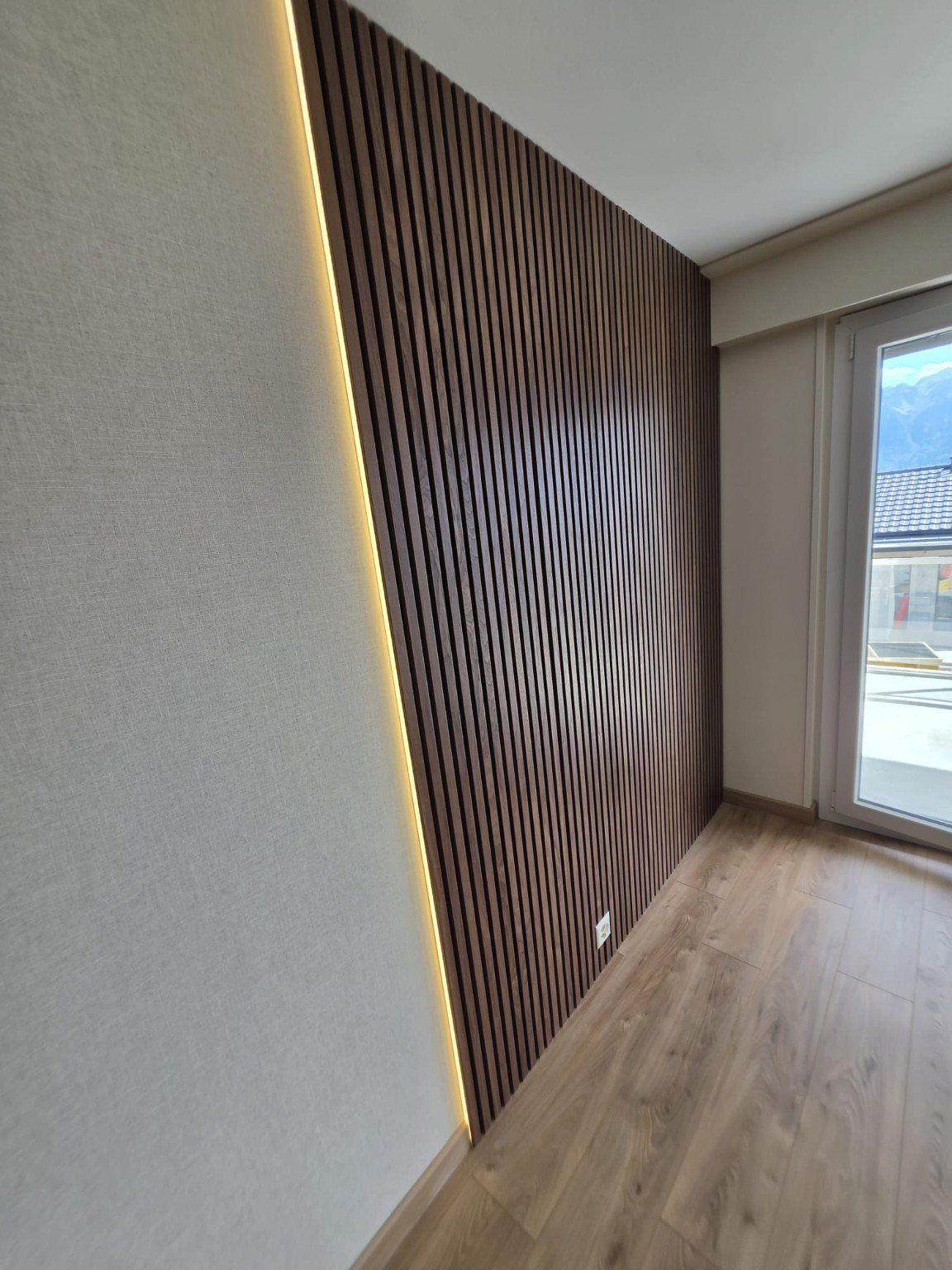 Détail du mur en tasseaux de bois et de son éclairage LED indirect