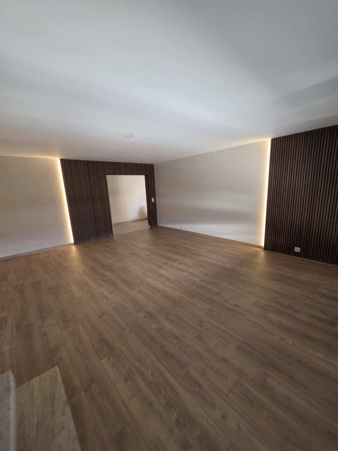 Séjour de l’appartement rénové à Vevey, avec habillages en tasseaux de bois et éclairage LED indirect
