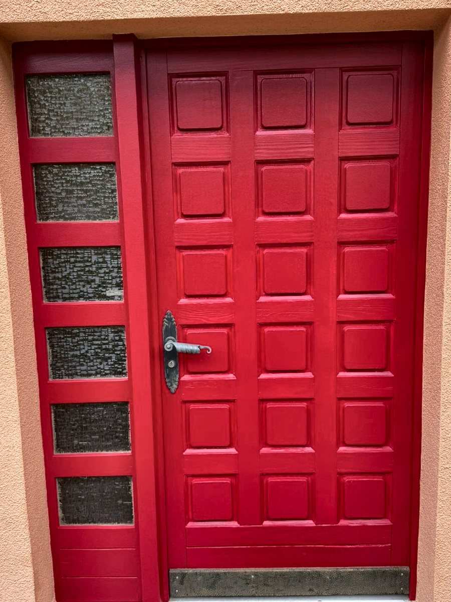 Porte d’entrée en bois rénovée à Yverdon-les-Bains, avec sa nouvelle finition rouge